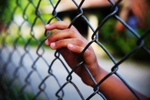 Child's hand on a chain link fence