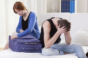 Wife packing and husband with head in his hands